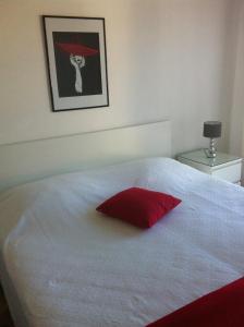 a white bed with a red pillow on it at Apartmani Antunović Podgora in Podgora
