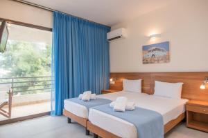 1 dormitorio con 2 camas y balcón en Lido Hotel, en Xylokastro