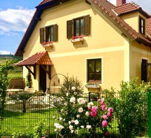 ein Haus mit Blumen vor einem Zaun in der Unterkunft Landhaus Weinblick in Rohrendorf bei Krems