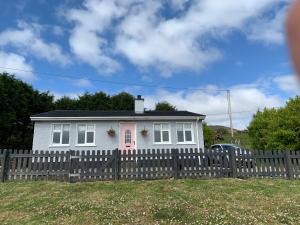 una casa blanca detrás de una valla de madera en Windmill cottage, en Donegal