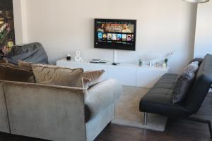 Una sala de estar con un sofá y un televisor en una pared. en FOROPLAZA Porta San Pedro Pleno Centro Vistas Muralla, en Lugo