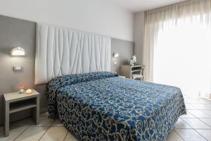 a bedroom with a blue bed and a window at Hotel Roland in Riccione