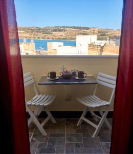 una mesa y sillas en un balcón con vistas en Mangion House en Marsaxlokk