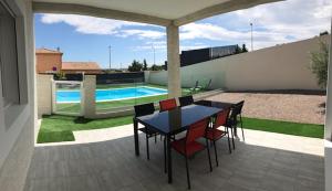 un patio con mesa y sillas y una piscina en Villa les agrumes, en Narbona