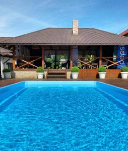 a large blue swimming pool in front of a house at Sadyba Lisova in Ternopilʼ