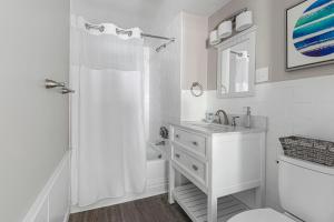 a white bathroom with a sink and a shower at The Cove at Rockport in Rockport