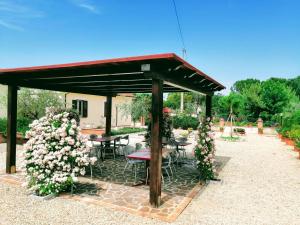 a pavilion with a table and chairs and flowers at Residence Terra Dei Santi Country House in Spello