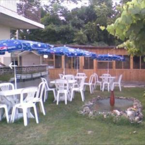 un grupo de mesas y sillas blancas con sombrillas en Krimski Guest House and Bungalows, en Byala