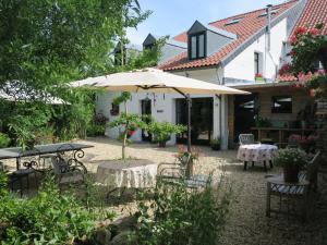 un patio con sombrilla, mesa y sillas en Kleebergerhofke en Mechelen
