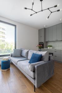 a living room with a gray couch and a kitchen at Portova Apartament in Gdynia