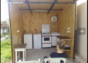 una mujer sentada frente a una pequeña cocina en Krimski bungalows, en Byala