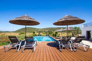 a deck with chairs and umbrellas and a pool at Quinta Tapada Do Gramacho in Silves