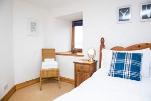 1 dormitorio con 1 cama y 1 silla en The Old Boathouse en Wormit