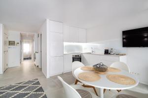 biała kuchnia z białym stołem i krzesłami w obiekcie Comtal homey apartments w Barcelonie