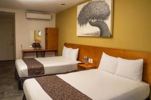 Cette chambre comprend 2 lits et une table. dans l'établissement AM Hotel y Plaza, à Santa Cruz Huatulco