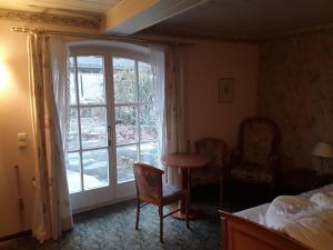Schlafzimmer mit einem Bett, einem Tisch und einem Fenster in der Unterkunft Hotel Feiler in Muggendorf
