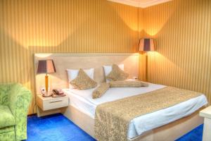 1 dormitorio con 1 cama con 2 almohadas y 1 silla en King Hotel Astana en Astaná