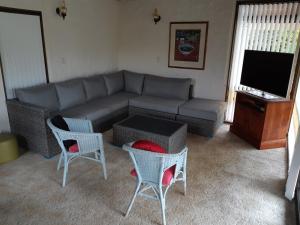Una sala de estar con un sofá y sillas y un televisor. en Wharepekapeka - Russell Holiday Home, en Russell