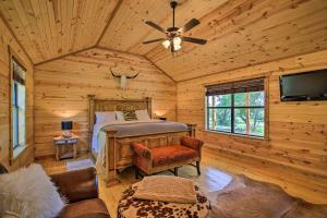 a bedroom in a log cabin with a bed and a tv at Rustic-Chic Country Cabin - 10 Mi to Main Street! in Fredericksburg