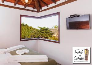a room with a window and a tv on the wall at Pousada Farol de Caraíva in Caraíva
