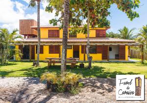 a yellow house with a picnic table in front of it at Pousada Farol de Caraíva in Caraíva