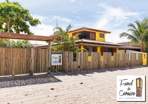 une maison sur la plage avec une clôture en bois dans l'établissement Pousada Farol de Caraíva, à Caraíva