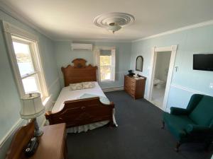 1 dormitorio con 1 cama, 1 silla y TV en The Tuna Blue Inn, en Hubbards