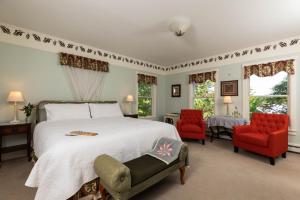 a bedroom with a bed and two red chairs at Maple Hill Farm Inn in Augusta