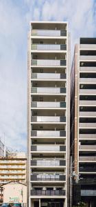 a tall white building in a city at Ostay Shin-Osaka Hotel Apartment in Osaka
