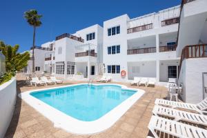 a swimming pool in front of a white building at Vista Mar Apartamentos in Puerto del Carmen