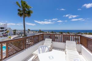 Un balcón con sillas blancas y vistas al océano. en Vista Mar Apartamentos, en Puerto del Carmen