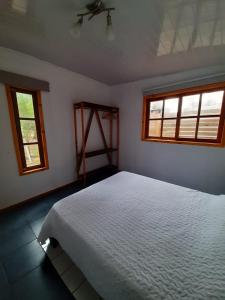 1 dormitorio con 1 cama blanca y 2 ventanas en Marittimo Cabañas, en José Ignacio
