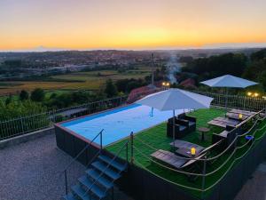 a swimming pool with chairs and umbrellas at sunset at Agriturismo Villa Bordone in Villafranca dʼAsti