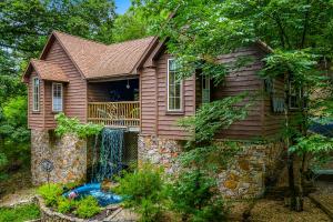 una casa con una cascada a un lado en The Woods Cabins, en Eureka Springs