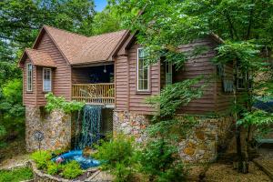 a house with a waterfall on the side of it at The Woods Cabins in Eureka Springs