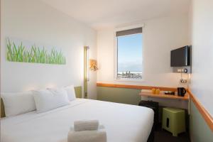 Habitación de hotel con cama blanca y ventana en ibis Budget Auckland Airport en Auckland