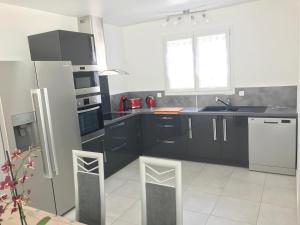 cocina con armarios negros y nevera blanca en Villa les agrumes, en Narbona