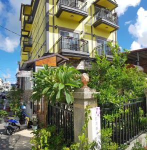 a yellow building with balconies and a fence at La Fleur BnB & Restaurant in Hengchun South Gate