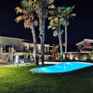 - une piscine dans une cour avec des palmiers la nuit dans l'établissement Villa Seba Sicily, à Augusta