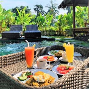 a table with plates of food and two drinks at Three Gold Luxury Private Villas in Ubud