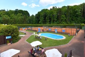 basen w parku z ludźmi siedzącymi wokół niego w obiekcie Pension Tenis - Centrum w Czeskim Krumlovie