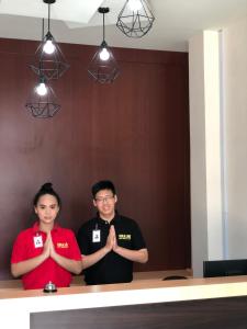 dwoje ludzi stojących rękami przed stołem w obiekcie Gold Line Guest House w mieście Pontianak