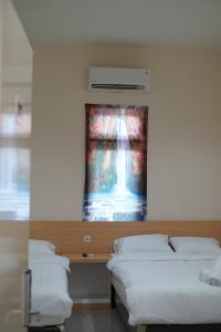 two beds in a room with a painting on the wall at Gold Line Guest House in Pontianak