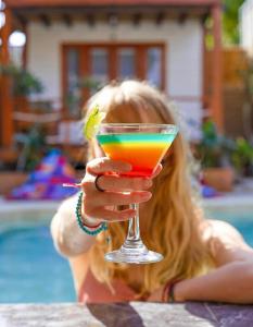 una chica sosteniendo una bebida colorida frente a una piscina en Voodoo Gili en Gili Trawangan