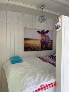 a bedroom with a picture of a cow on the wall at Little blue house (on the campsite) in Oostvoorne