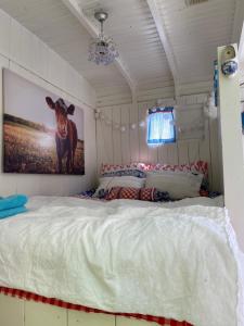 a bedroom with a bed with a picture of a cow on the wall at Little blue house (on the campsite) in Oostvoorne