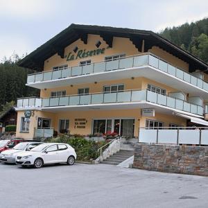 a building with two cars parked in front of it at Hotel La Reserve in Sankt Niklaus