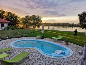 a swimming pool in a yard with chairs and a lake at Vila Lily in Smederevo