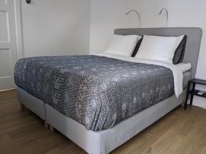 a bed with a gray comforter and white pillows at Beachtime Suite in Zandvoort