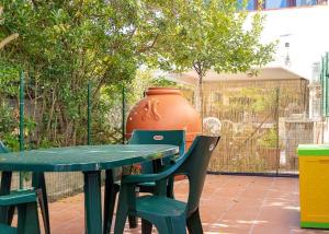 una mesa verde y sillas con un jarrón grande en Maria grazia en Casa Alzi